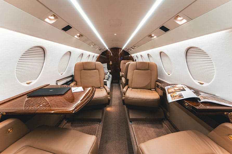 The Falcon 7X cabin is spacious and well-lit, with comfortable seating and tables.