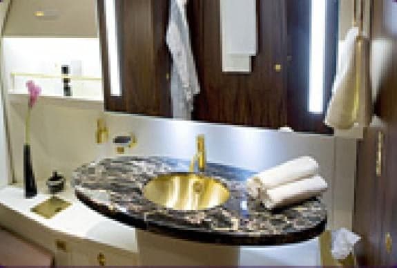 A private jet bathroom with a marble countertop and gold fixtures.