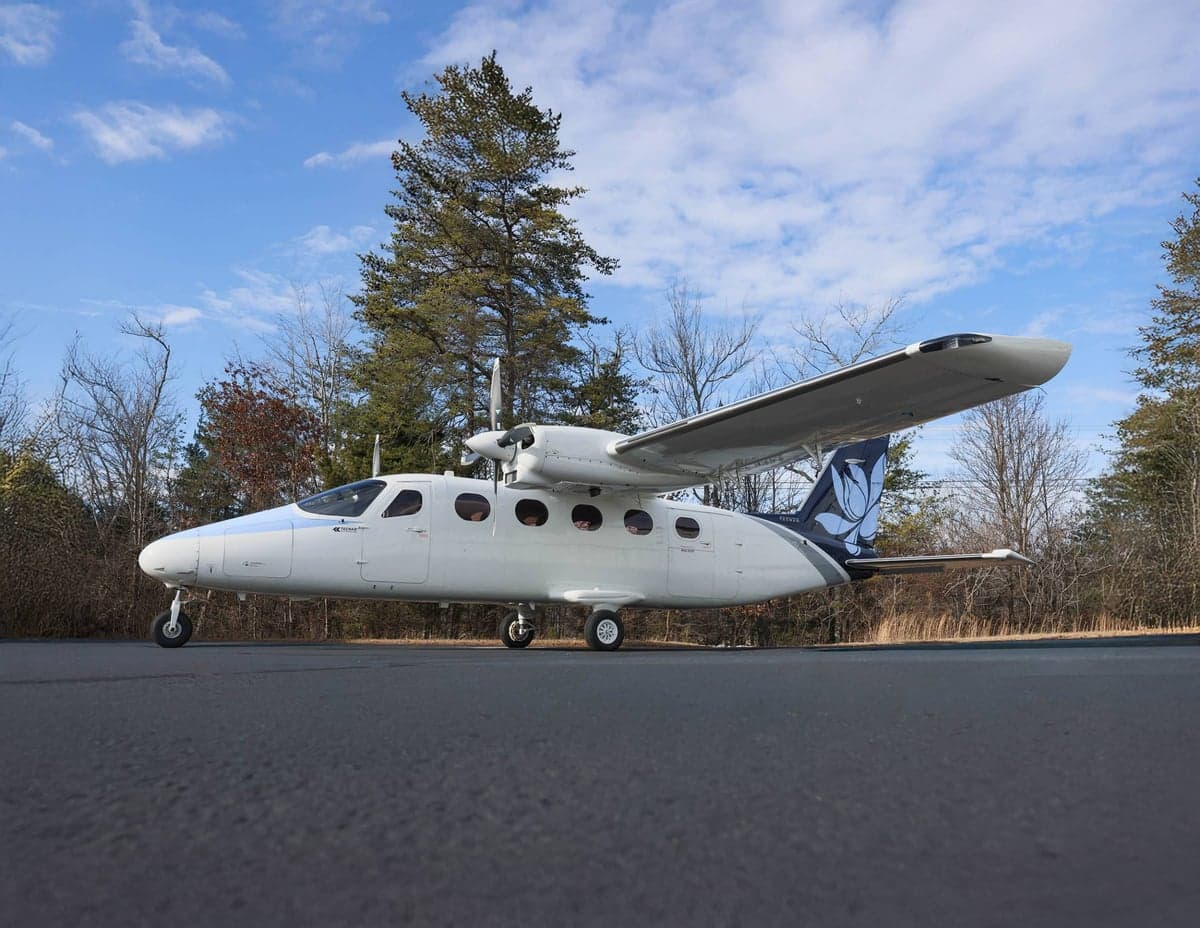 Side view of a white and blue Tecnam P2012 Traveller aircraft on the ground.