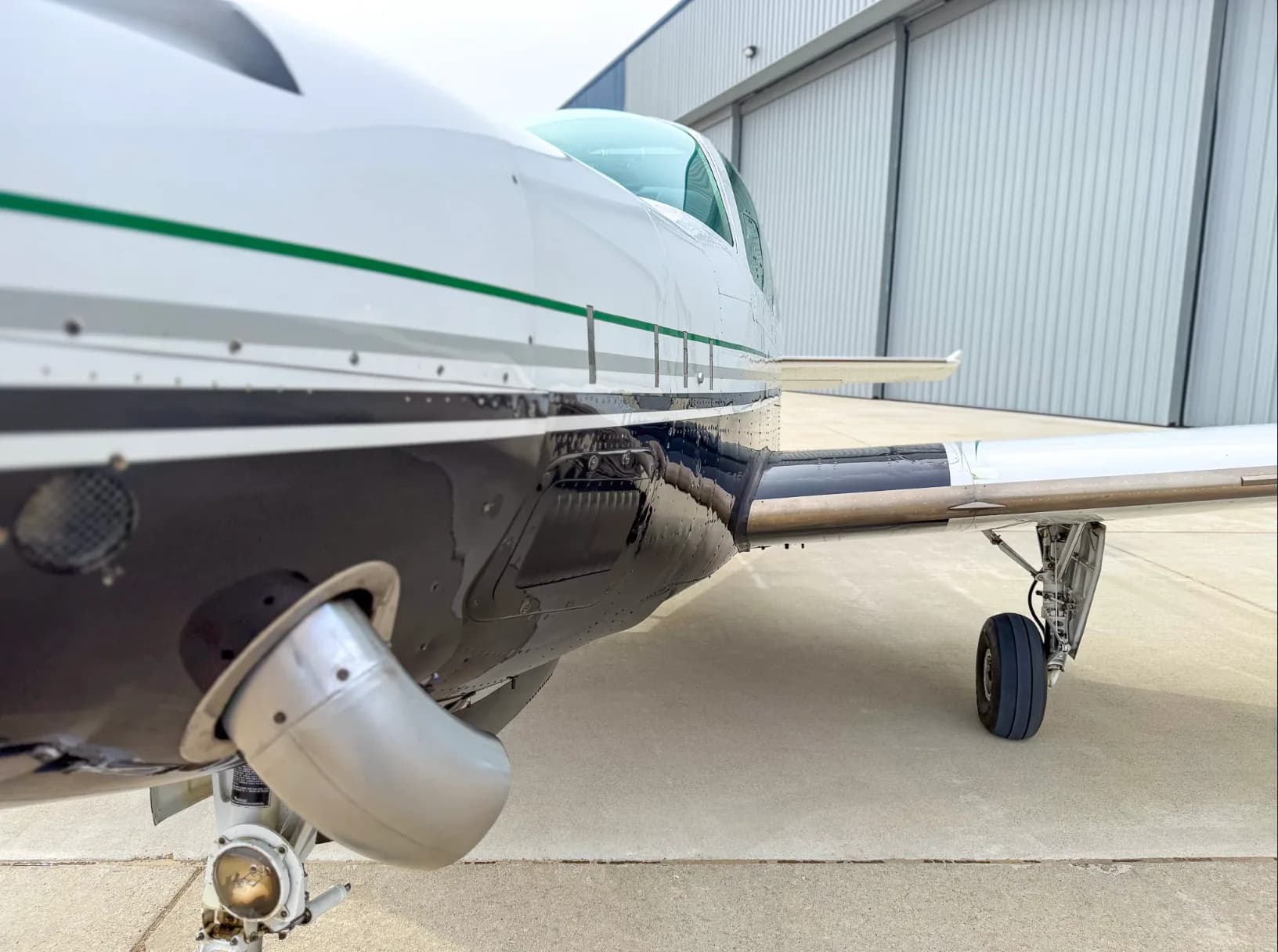 A close-up side view of the engine cowling and landing gear of the Beechcraft Baron N157BA.