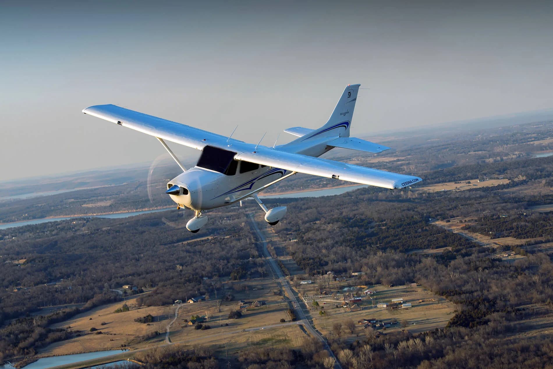 A Cessna 172 Skyhawk in flight over a rural landscape.