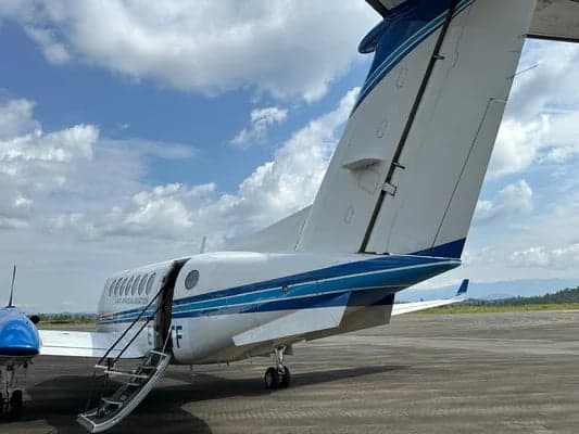 Rear view of the King Air aircraft on the tarmac, showing the tail and open airstair door.