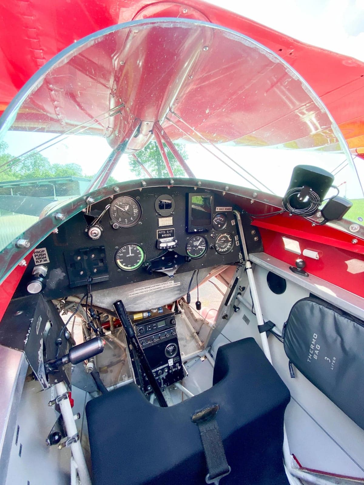 A red and white Pitts S-1T biplane with registration N49325 parked on the grass.