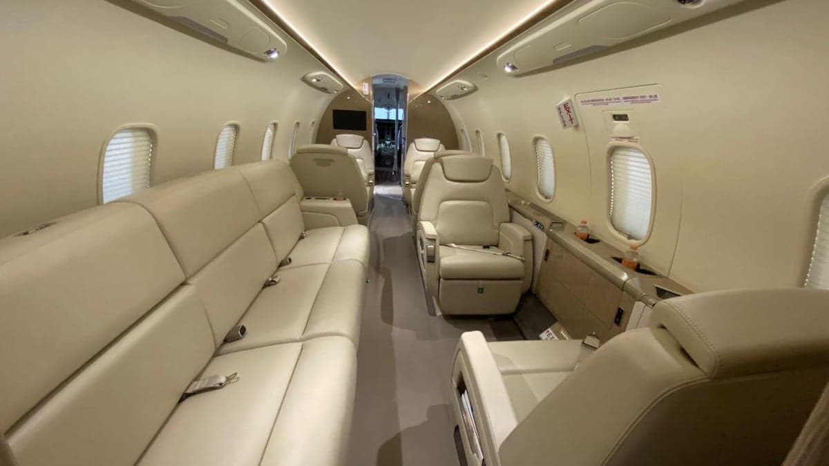 View of the aircraft cabin with cream-colored leather seats and a sofa.