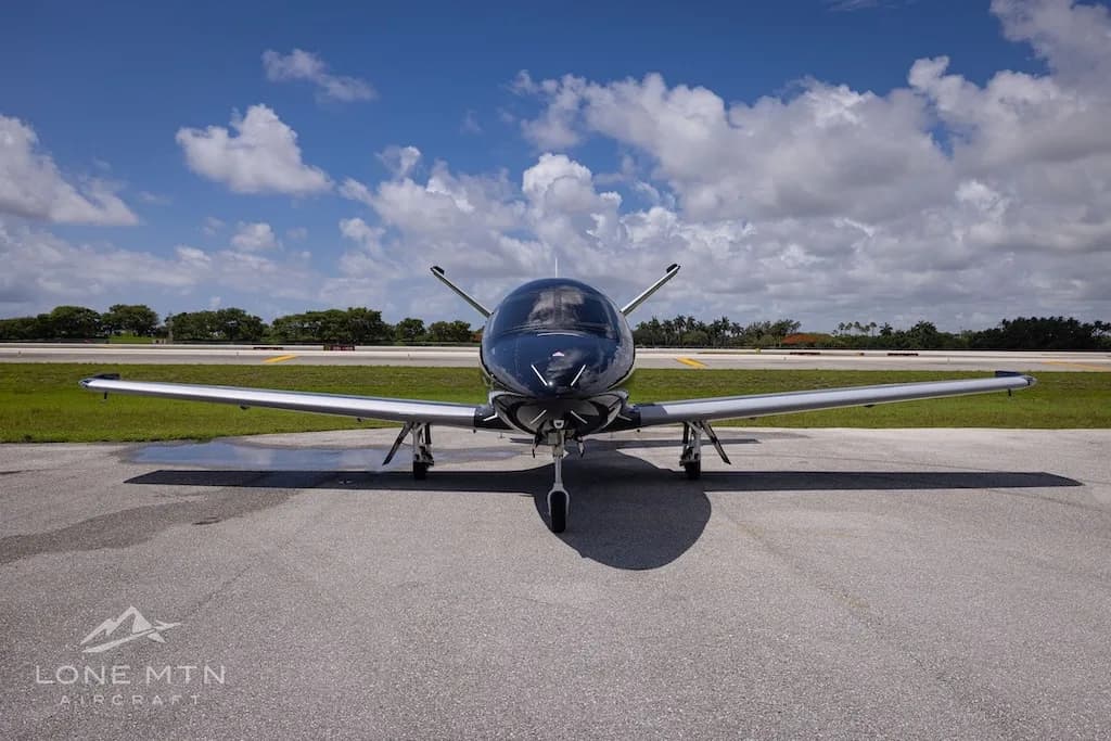 A black Cirrus Vision Jet (N300VJ) with silver accents parked on an airport tarmac, viewed head-on.
