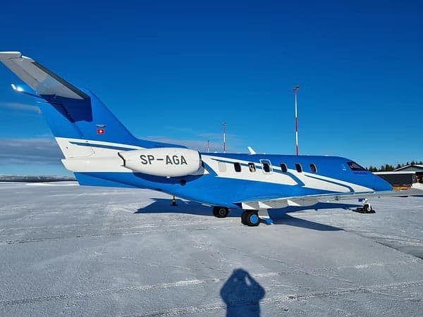 A blue and white Pilatus PC-24 with registration SP-AGA on a snowy airfield.