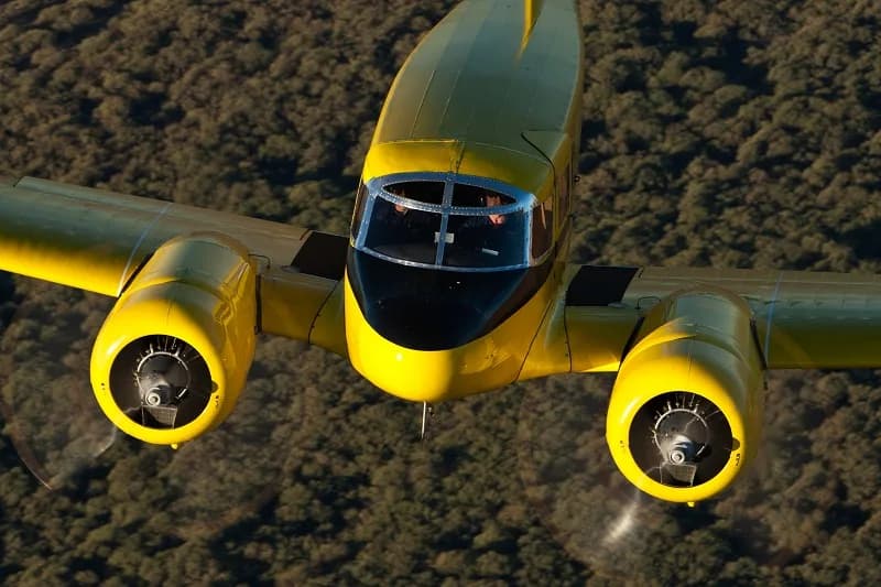 Close up of a yellow Beechcraft Model 18 in flight.