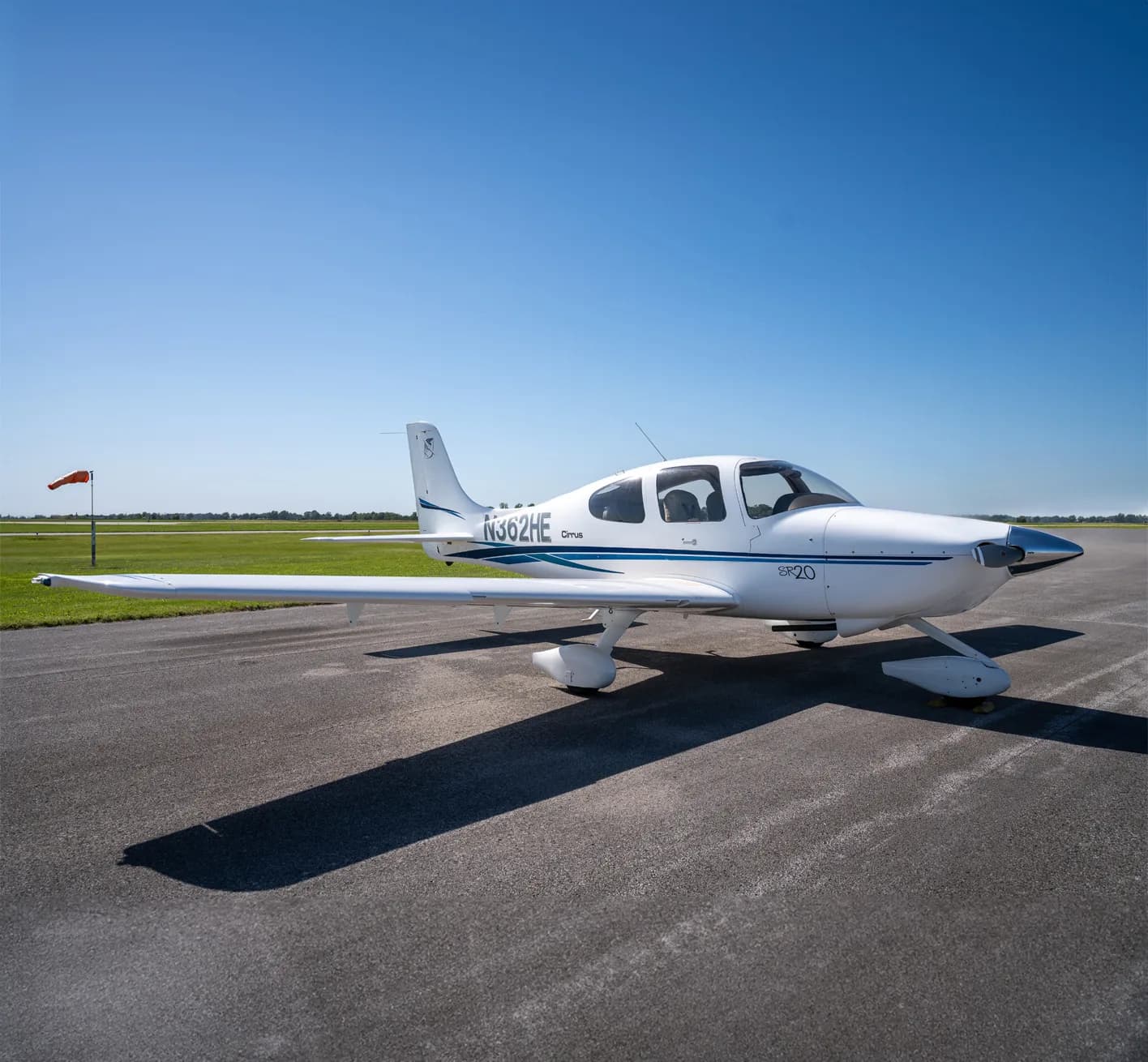 A Cirrus SR20 aircraft is parked on the tarmac.