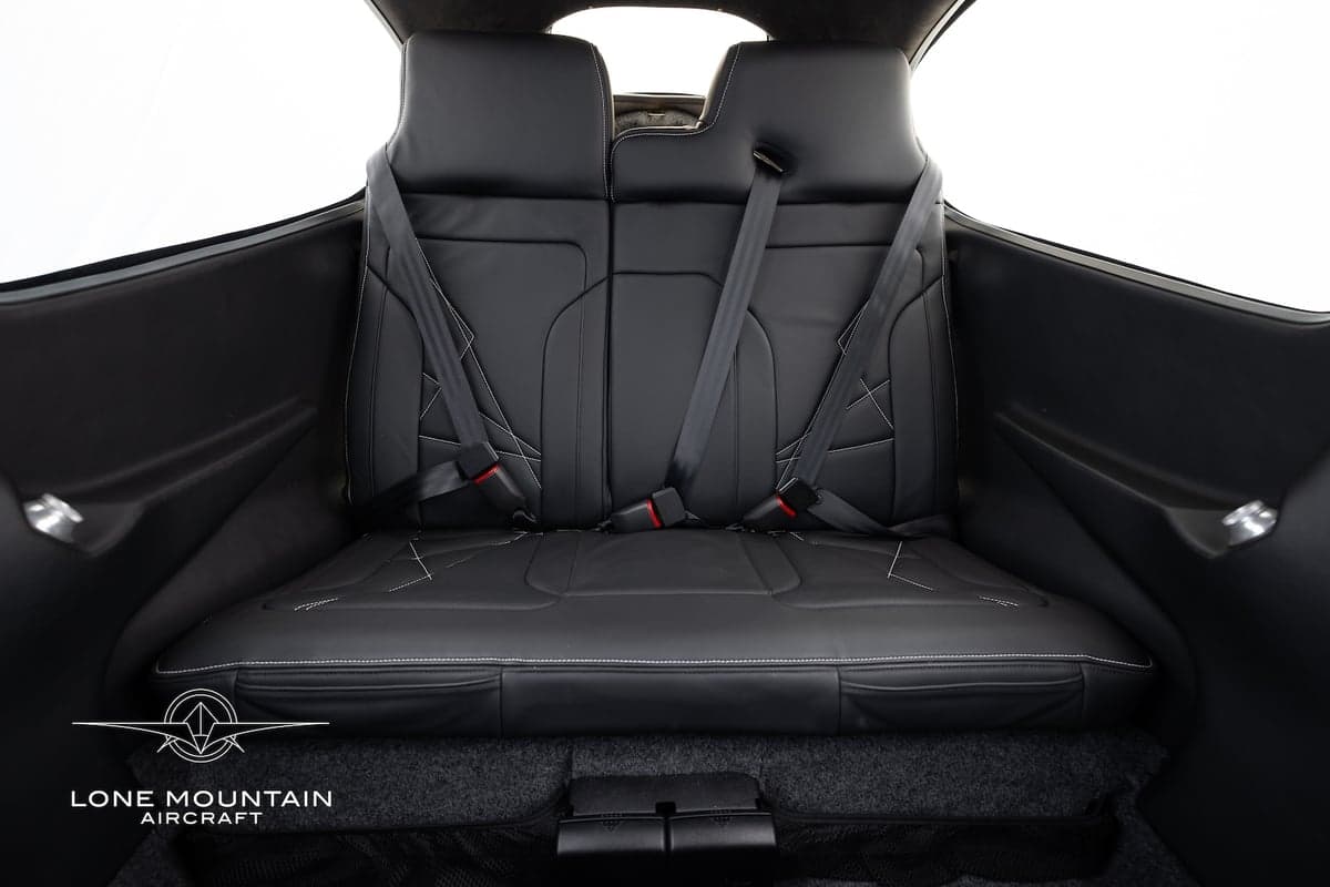 Rear bench seat of the Cirrus SR22T aircraft, showing the black leather upholstery and seatbelts.