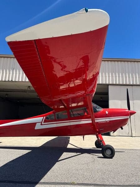 Side view of the red and white Cessna Skywagon 180 on the tarmac.