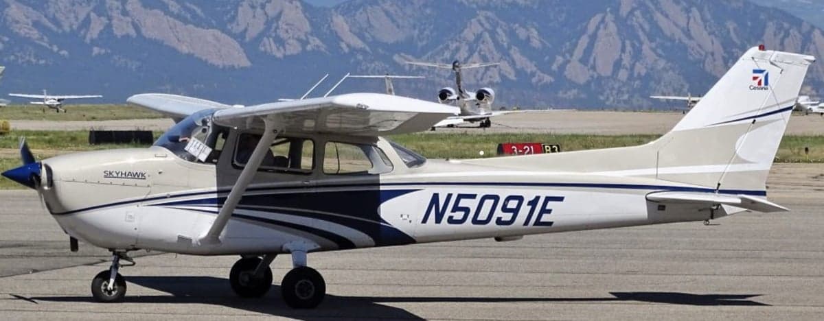 A Cessna Skyhawk with a white and blue paint scheme is parked on the tarmac.
