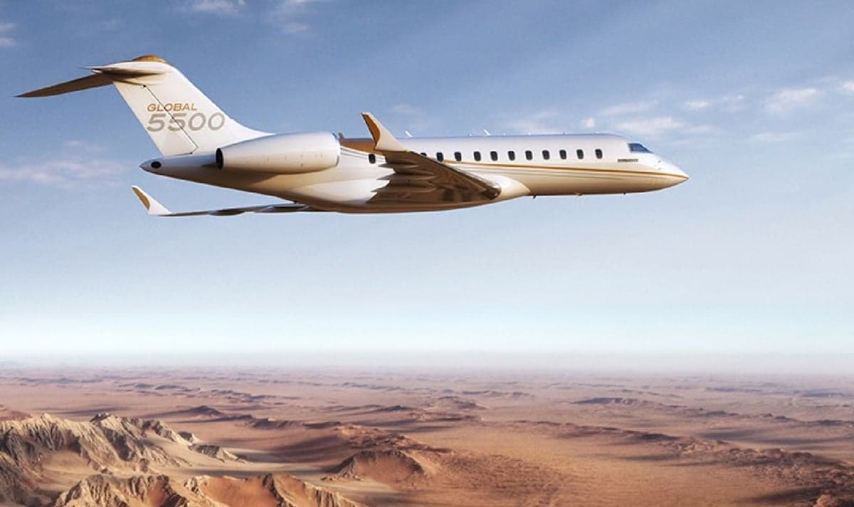 A Bombardier Global 5500 flying over a desert landscape.