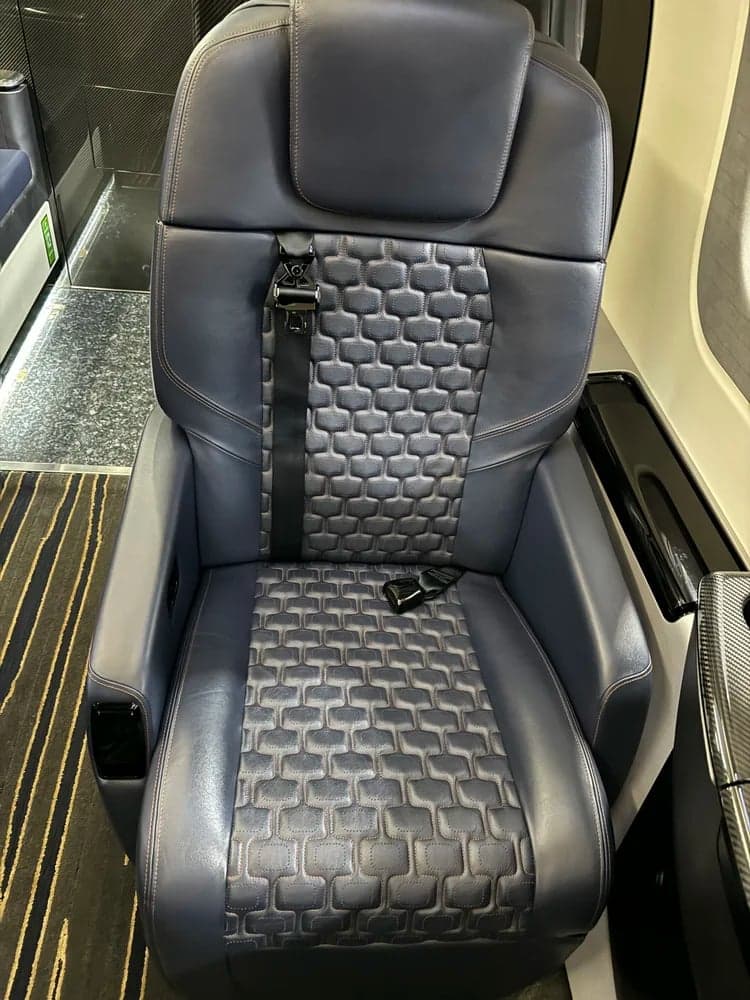 Close-up of a single blue leather aircraft seat with patterned insert.