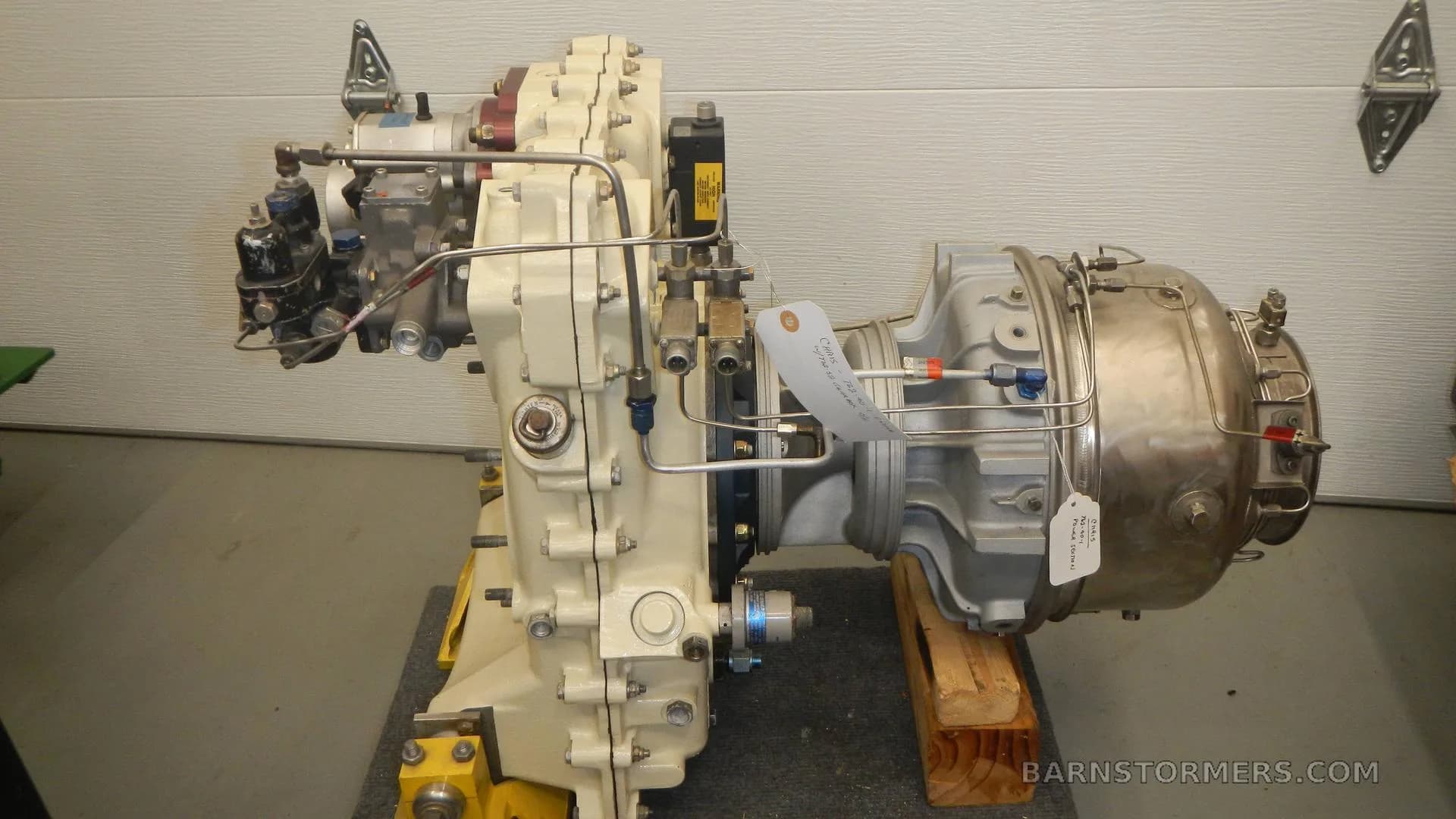 A side view of a turboprop or turboshaft aircraft engine with various pipes and components visible.