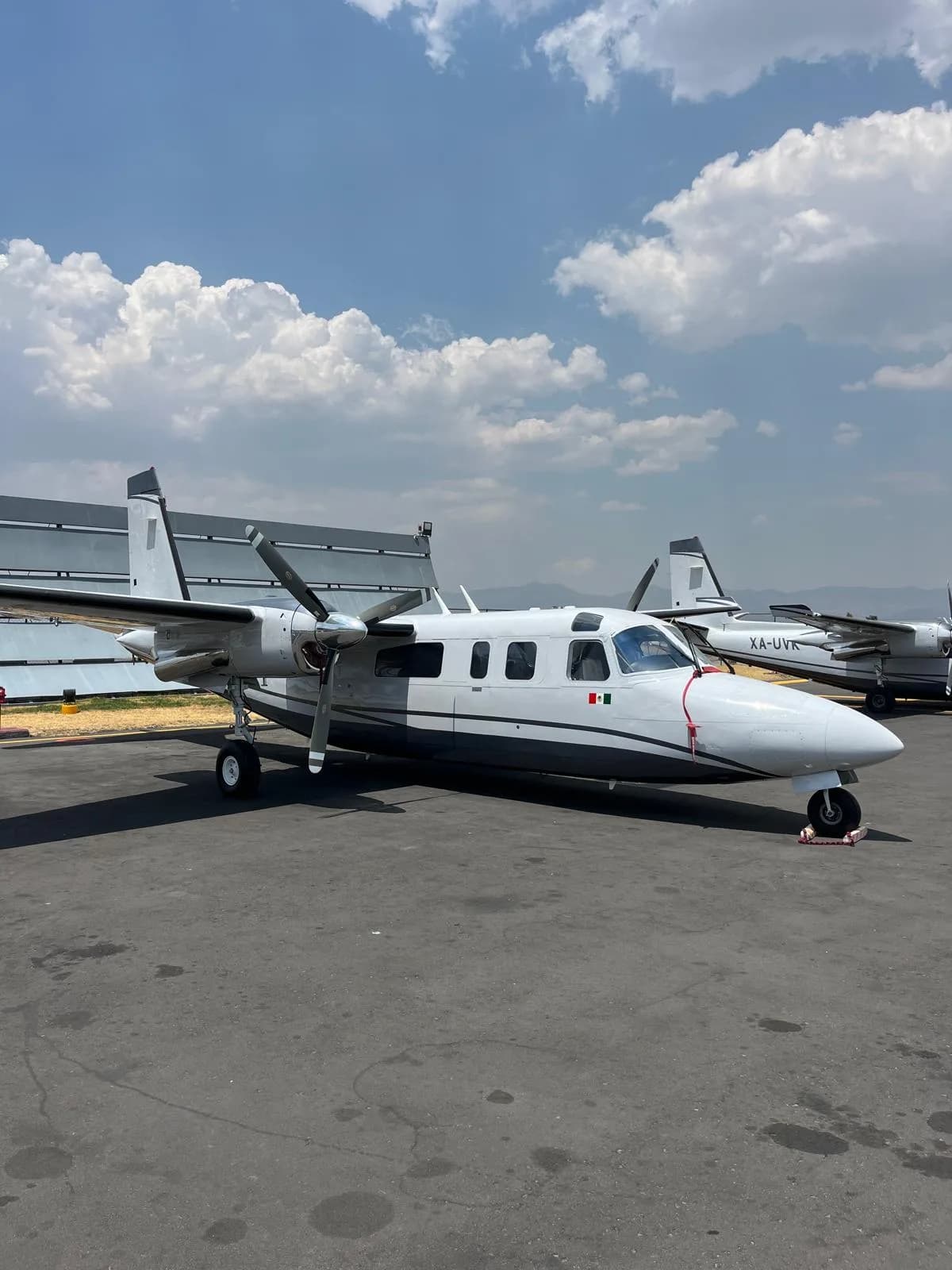 A white and gray aircraft sits on the tarmac under a cloudy sky.
