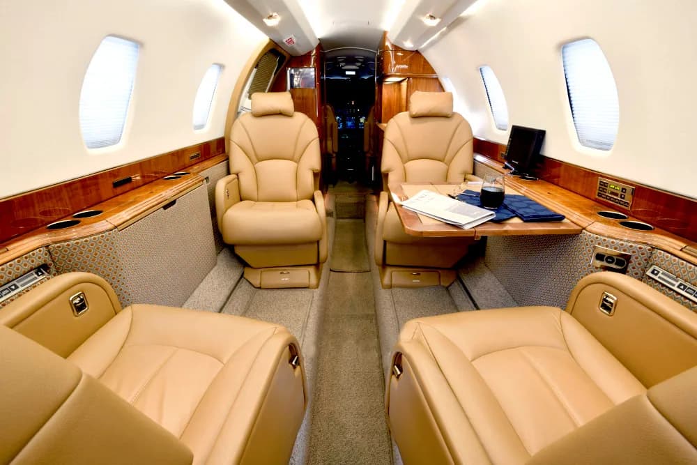 Aircraft interior with tan leather seats and wood trim.