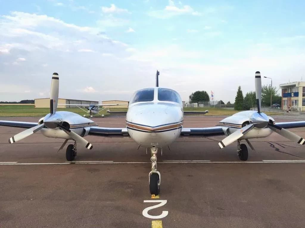 Front view of a white Cessna 421 Golden Eagle aircraft with twin propellers on an airfield.