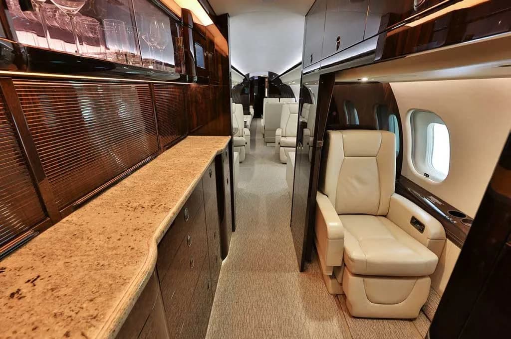 A view of the business jet's galley area with a countertop and storage, looking towards the passenger cabin.