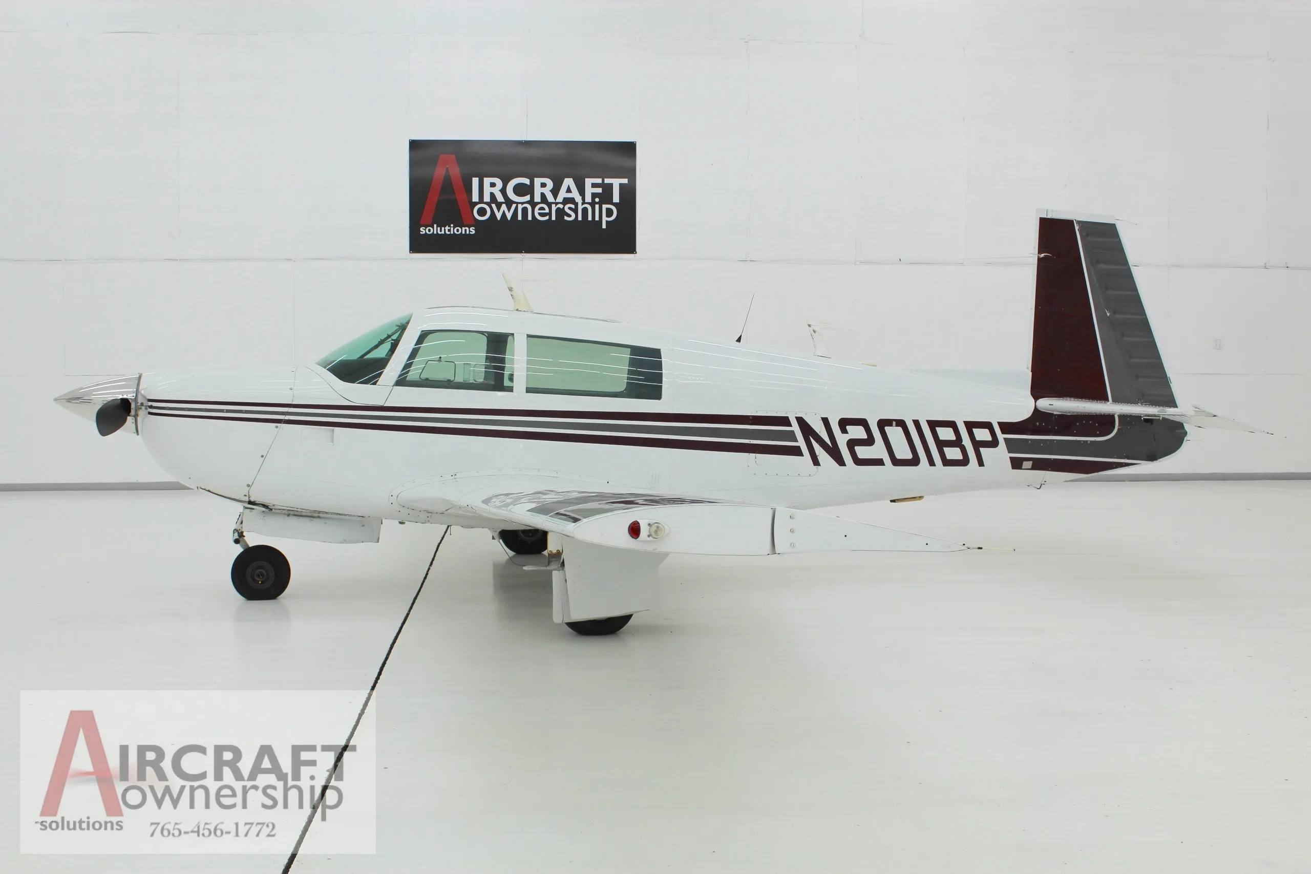 Side view of the white and brown N201BP aircraft in a hangar.