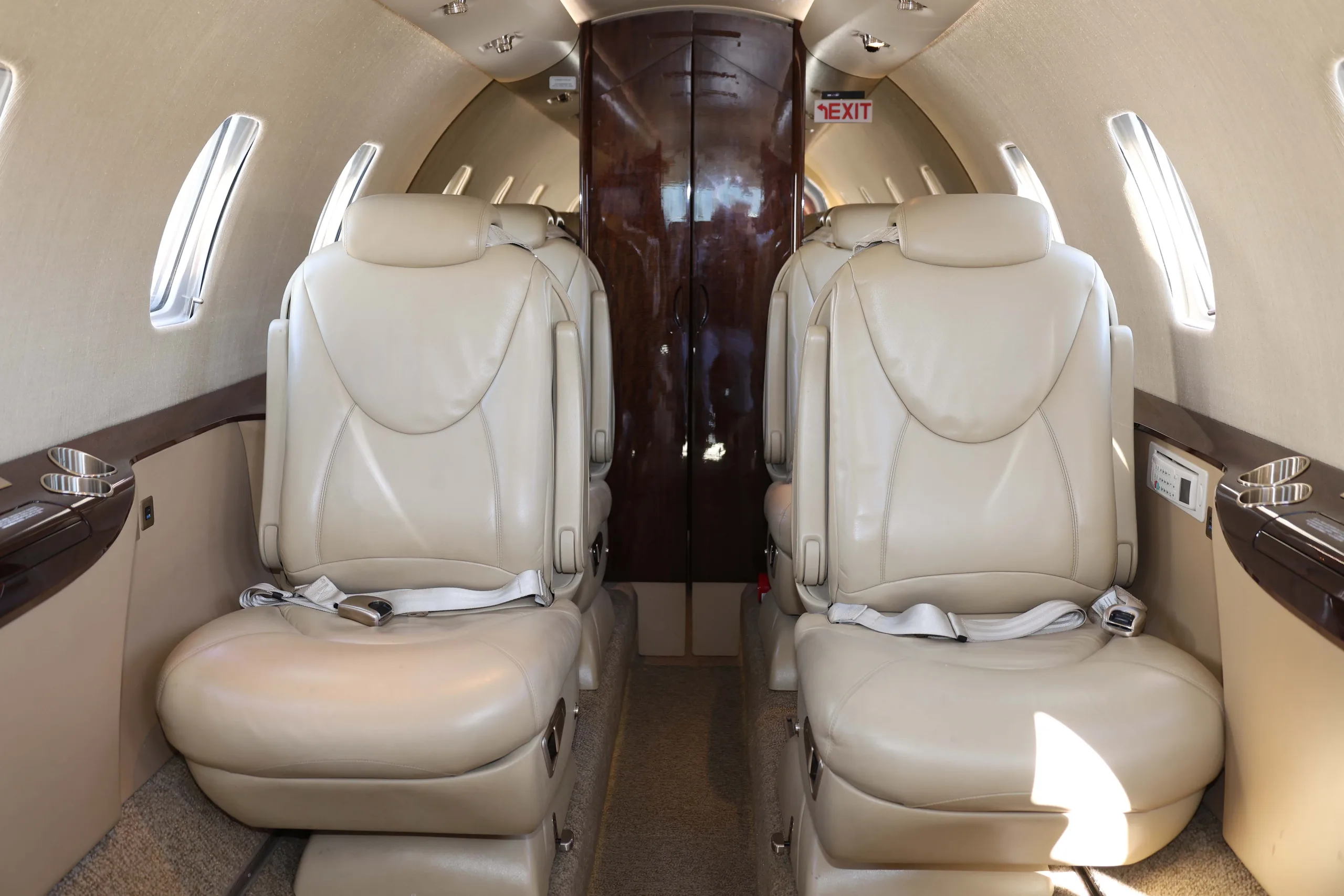 The aircraft cabin interior with light tan leather seats looking towards the rear.