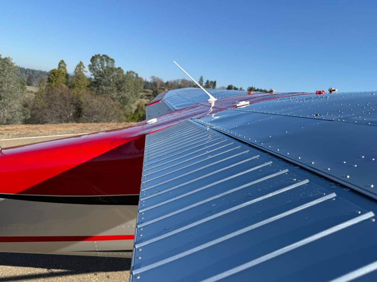 Close-up of the wing of the N2771C aircraft, showing the silver and red paint scheme.