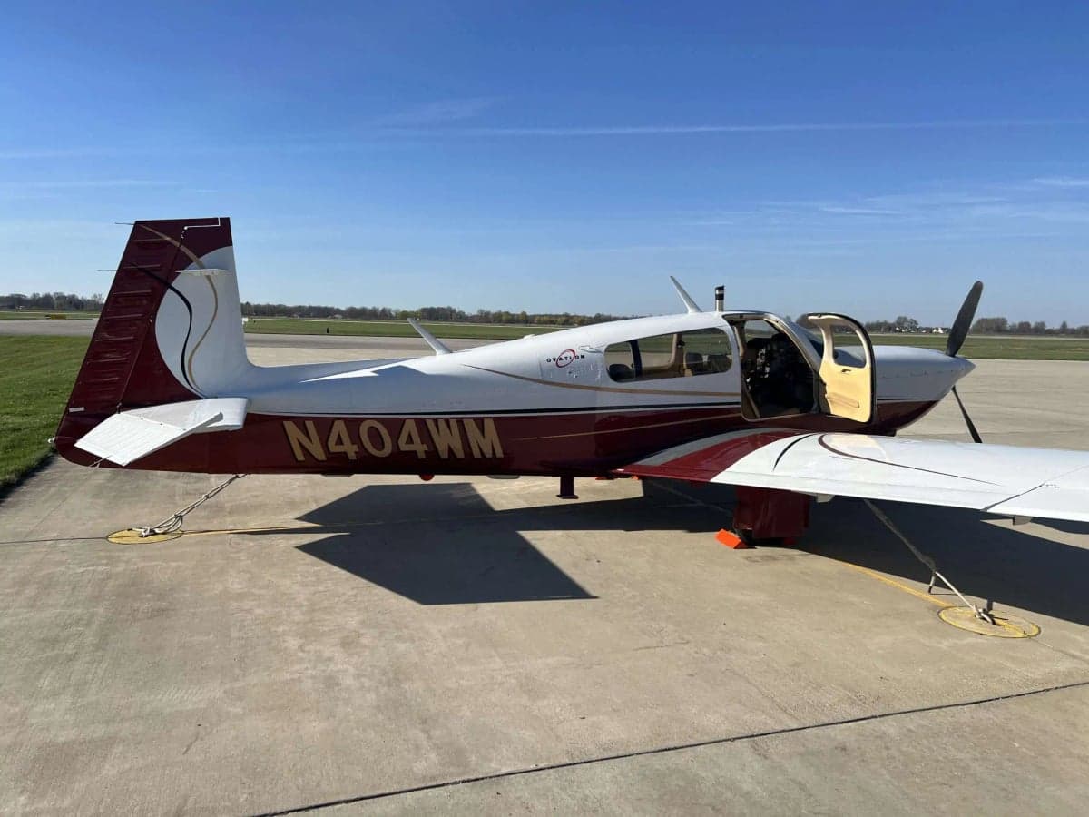 Mooney M20J with a white and maroon paint scheme parked on the tarmac with the door open.