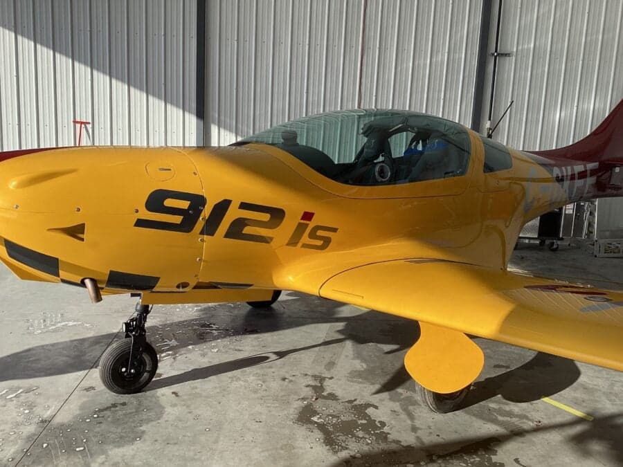 Close-up side view of a yellow VL3 Evolution aircraft inside a hangar.