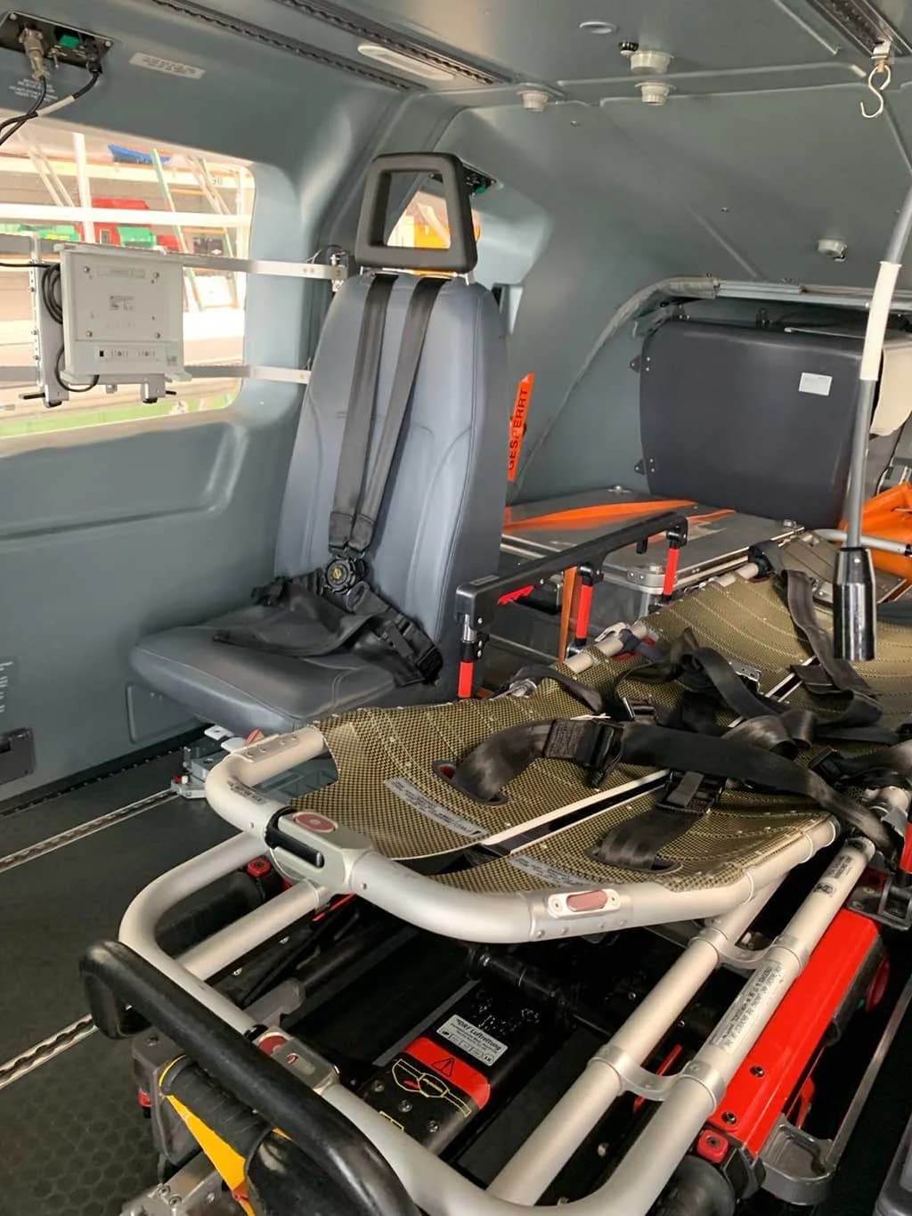 The interior cabin of a helicopter, showing an EMS configuration with a stretcher and a single crew seat.