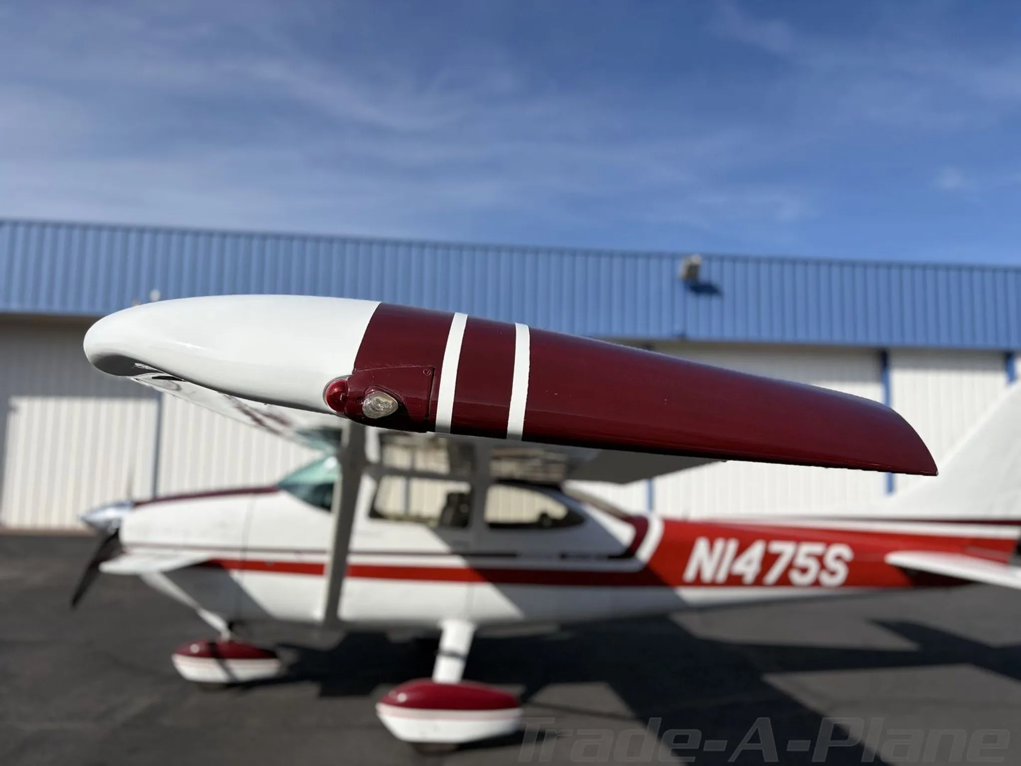 A focused view of the right wingtip with the white and red Cessna Skylane II (N1475S) blurred in the background.