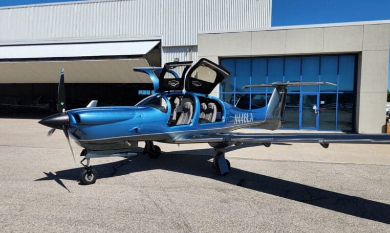 Diamond DA50 RG aircraft N446LA parked in front of a hangar with open doors.