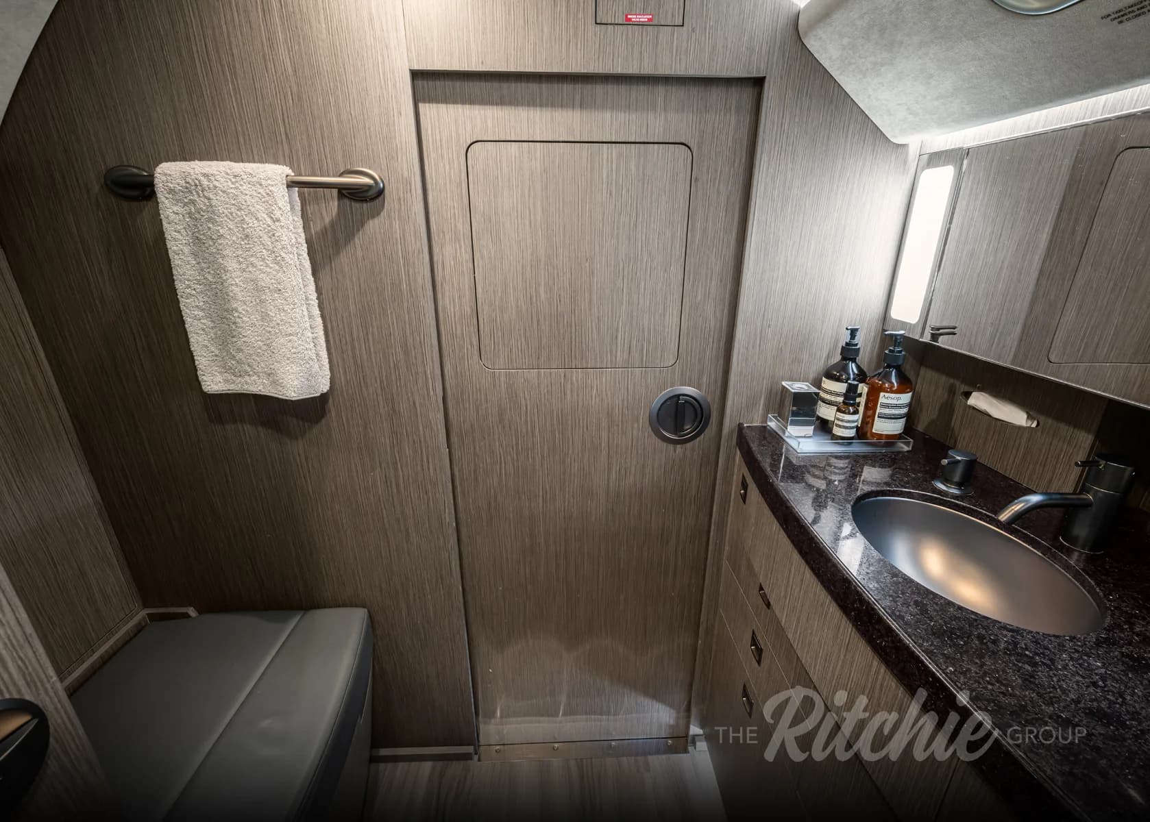 The lavatory of the Gulfstream G650, with a sink, mirror, and a towel hanging on the wall.