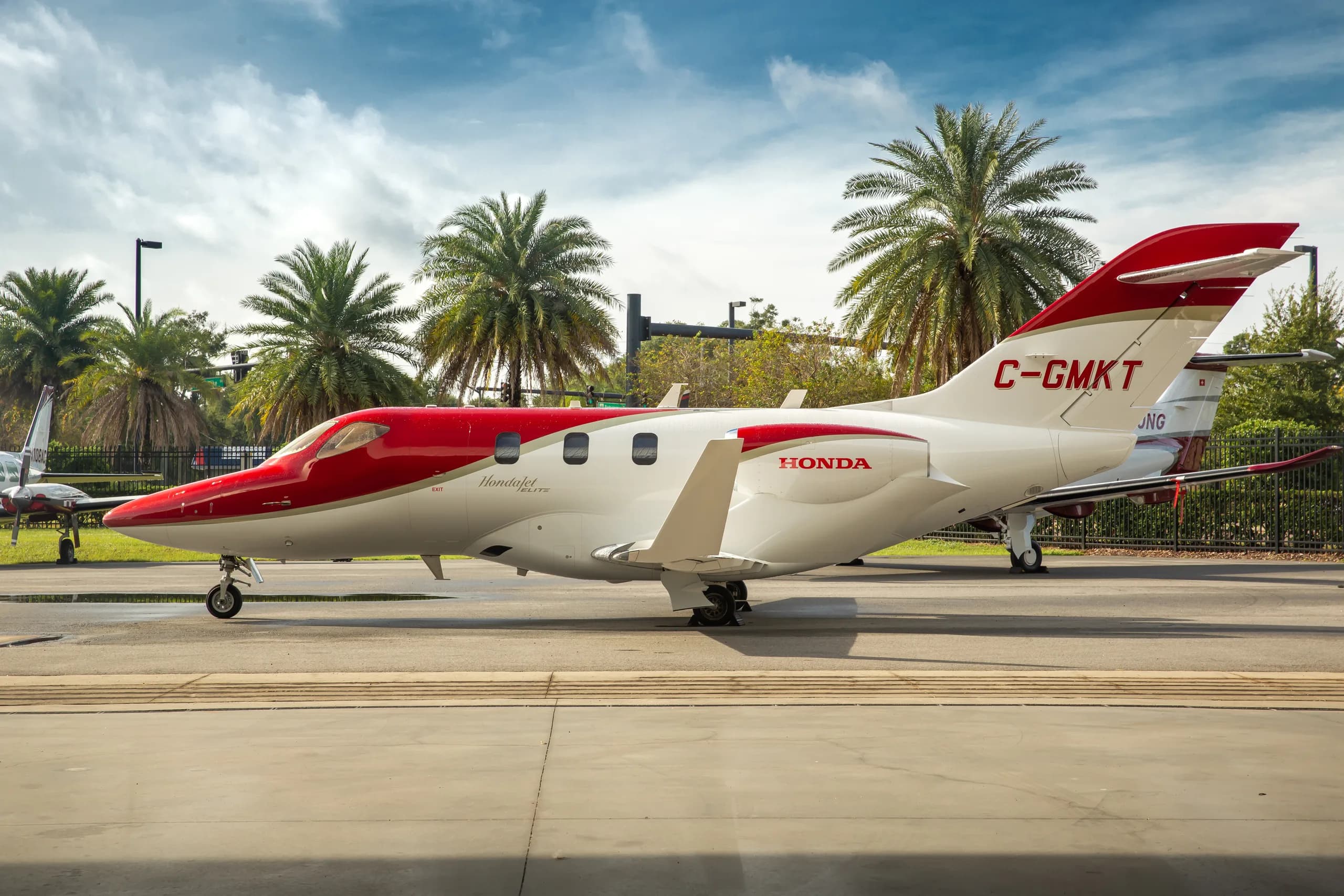 A red and white HondaJet with registration C-GMKT parked on an tarmac, viewed from the side.