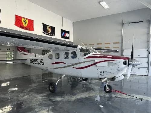 A Cessna 208 Caravan with a white and red paint scheme is parked in a hangar.