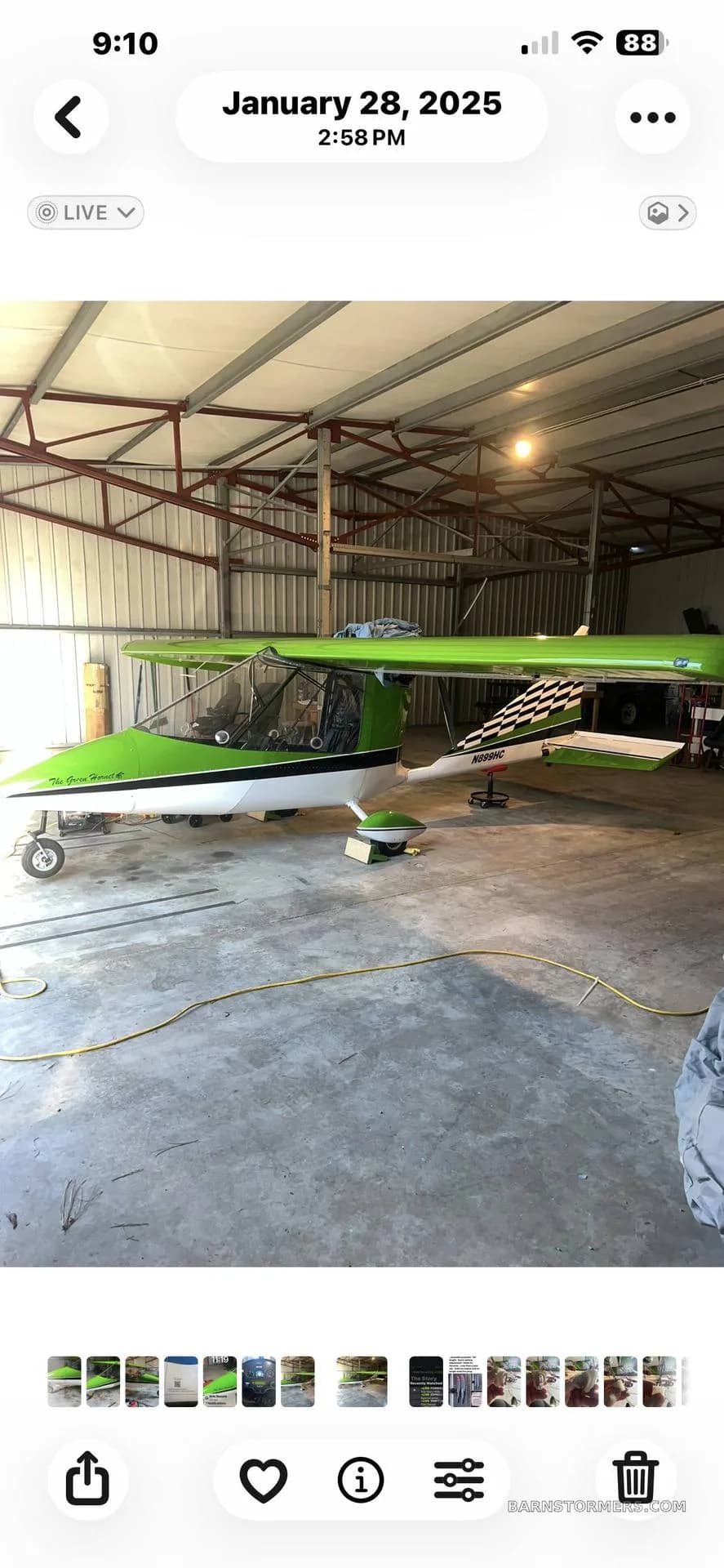 A bright green and white ultralight aircraft with a checkered tail is parked inside a hangar.