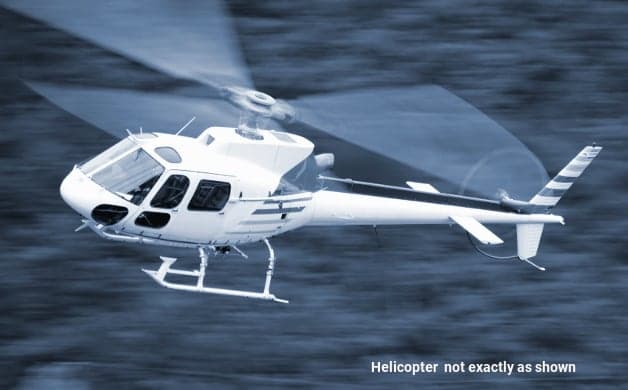 A white helicopter, possibly an Eurocopter AS350, flying against a blurred background.