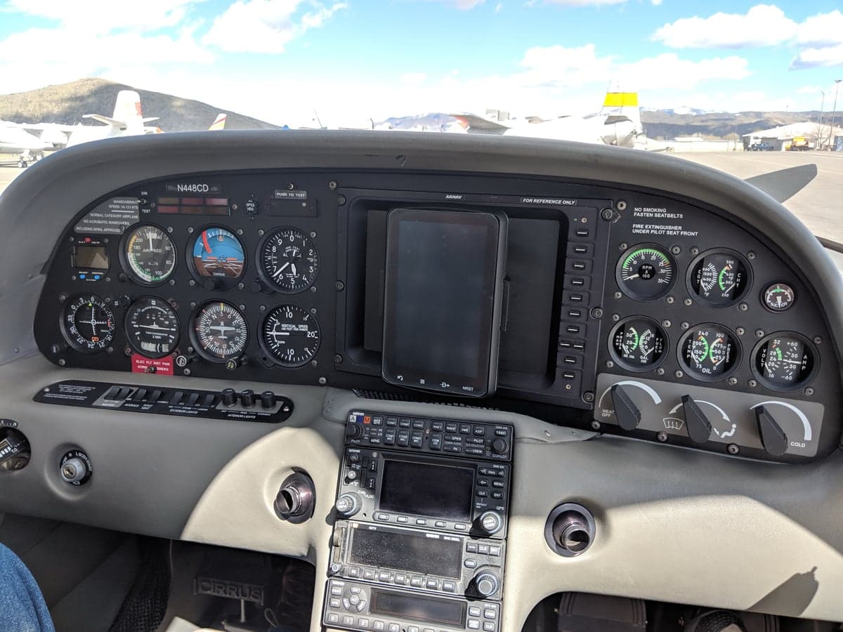 The cockpit of a Cirrus SR20, showing the instrument panel with analog gauges and a tablet mounted in the center.