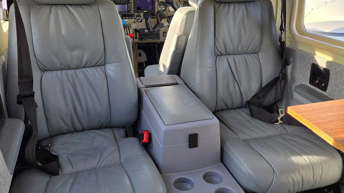 Close-up of the aircraft's gray leather seats and center console with cupholders.