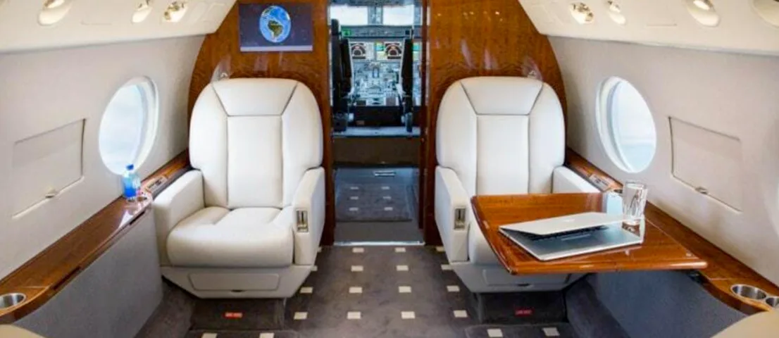 A view of the aircraft's interior with white leather seats and wood trim.