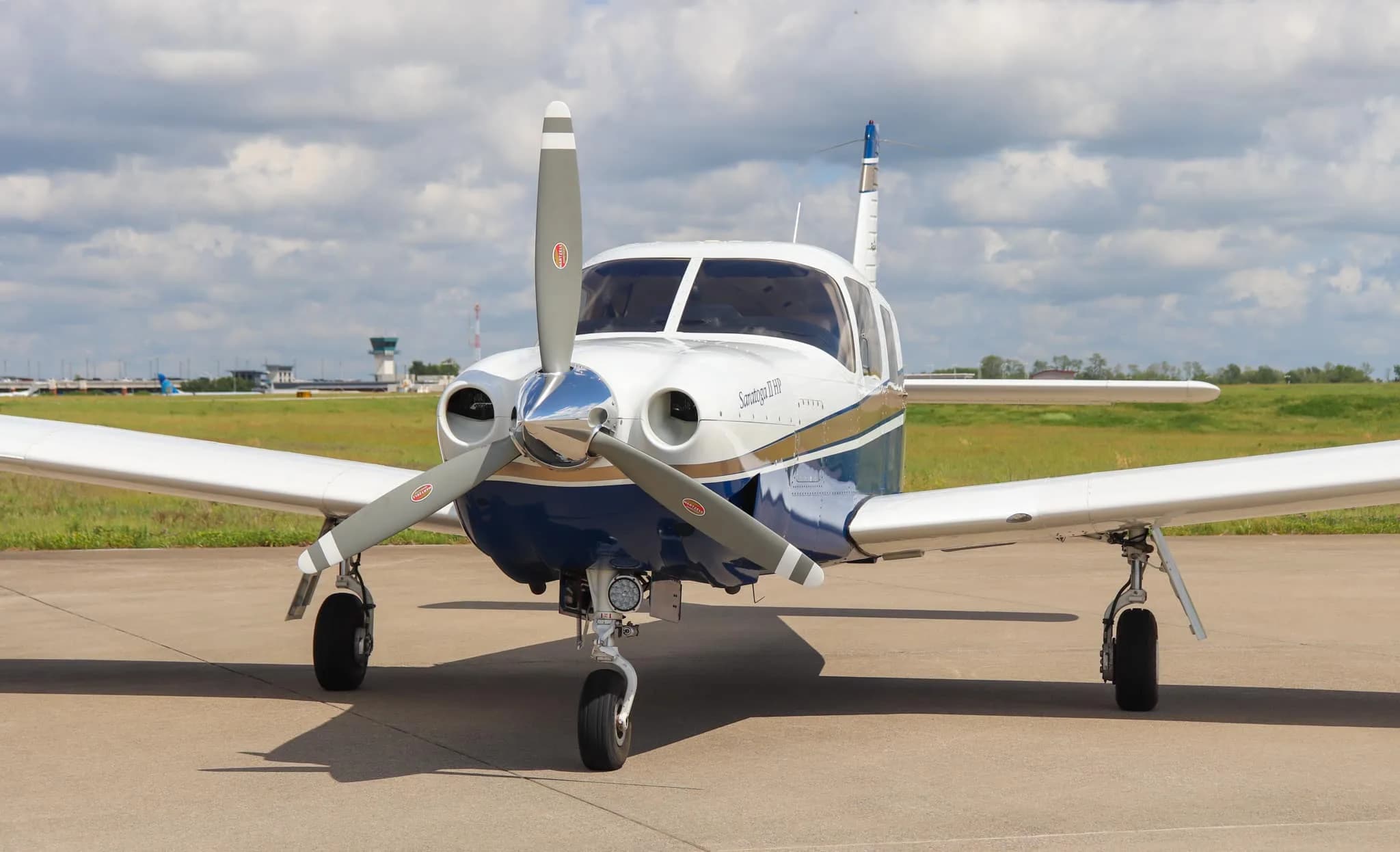A front three-quarter view of the Piper Saratoga II HP aircraft, N954K, on an airfield under a cloudy sky.