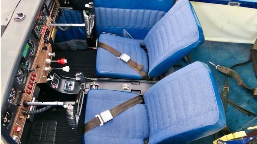 The aircraft's interior features blue seats and a control panel.