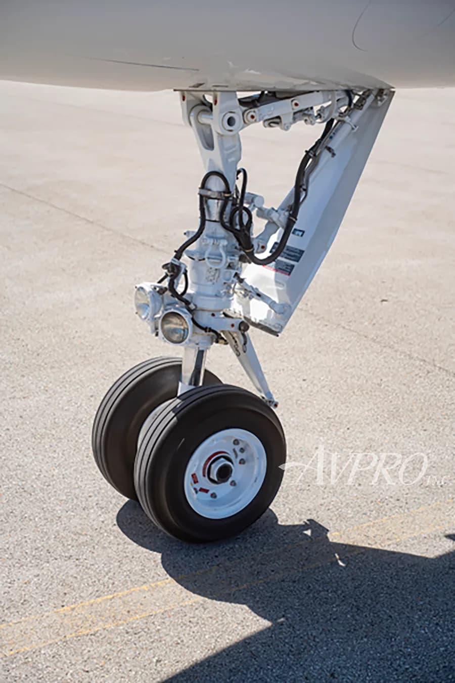 A close-up view of the main landing gear with two wheels on the tarmac.