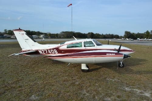 A Beechcraft Baron with tail number N27408 is parked on the grass.
