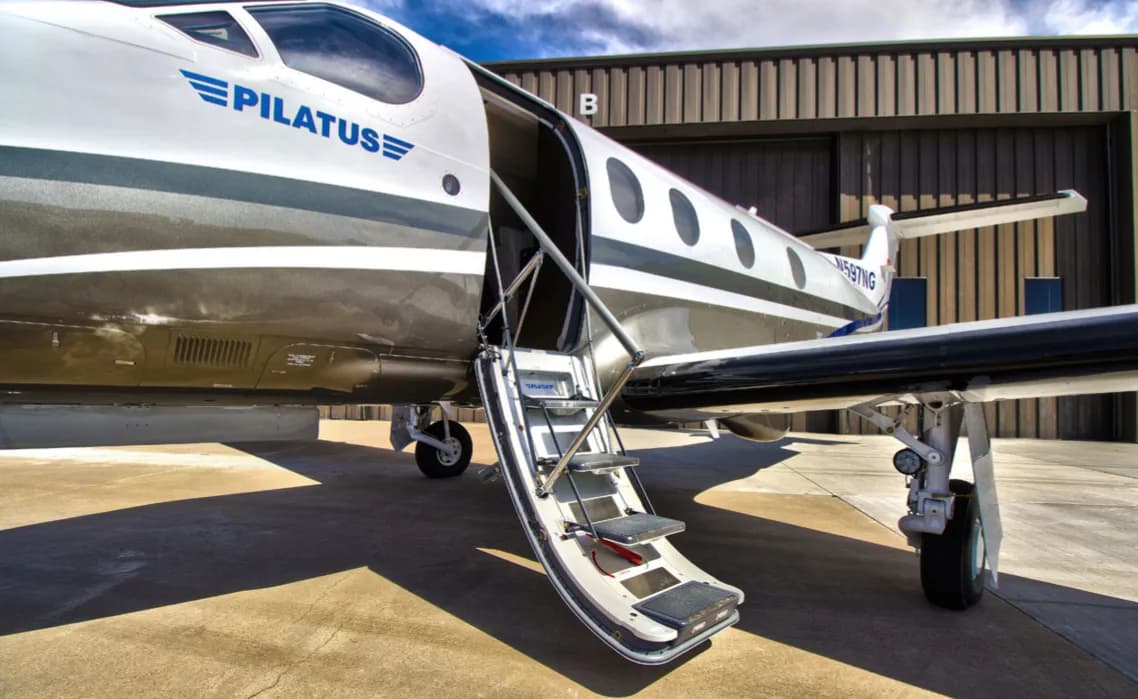 A Pilatus PC-12 with the door open and stairs extended.