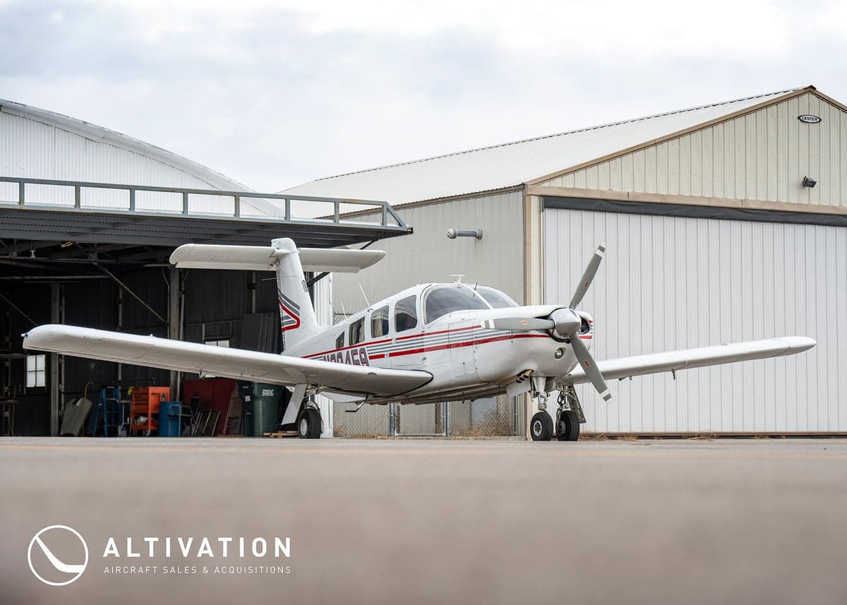 A Piper PA-28-181 Archer II parked in front of a hangar.
