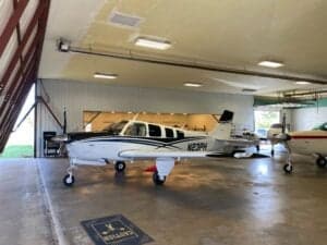 A Beechcraft Bonanza sits in a hangar.