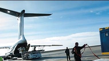 The rear of a cargo plane being loaded with cargo containers.