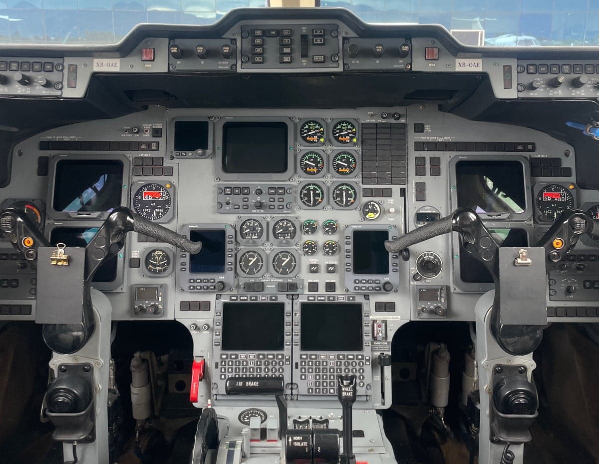 The detailed cockpit of a business jet, featuring multiple screens, gauges, and control yokes.