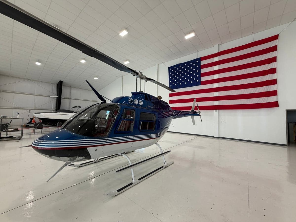 A blue and white helicopter parked in a hangar with an American flag.