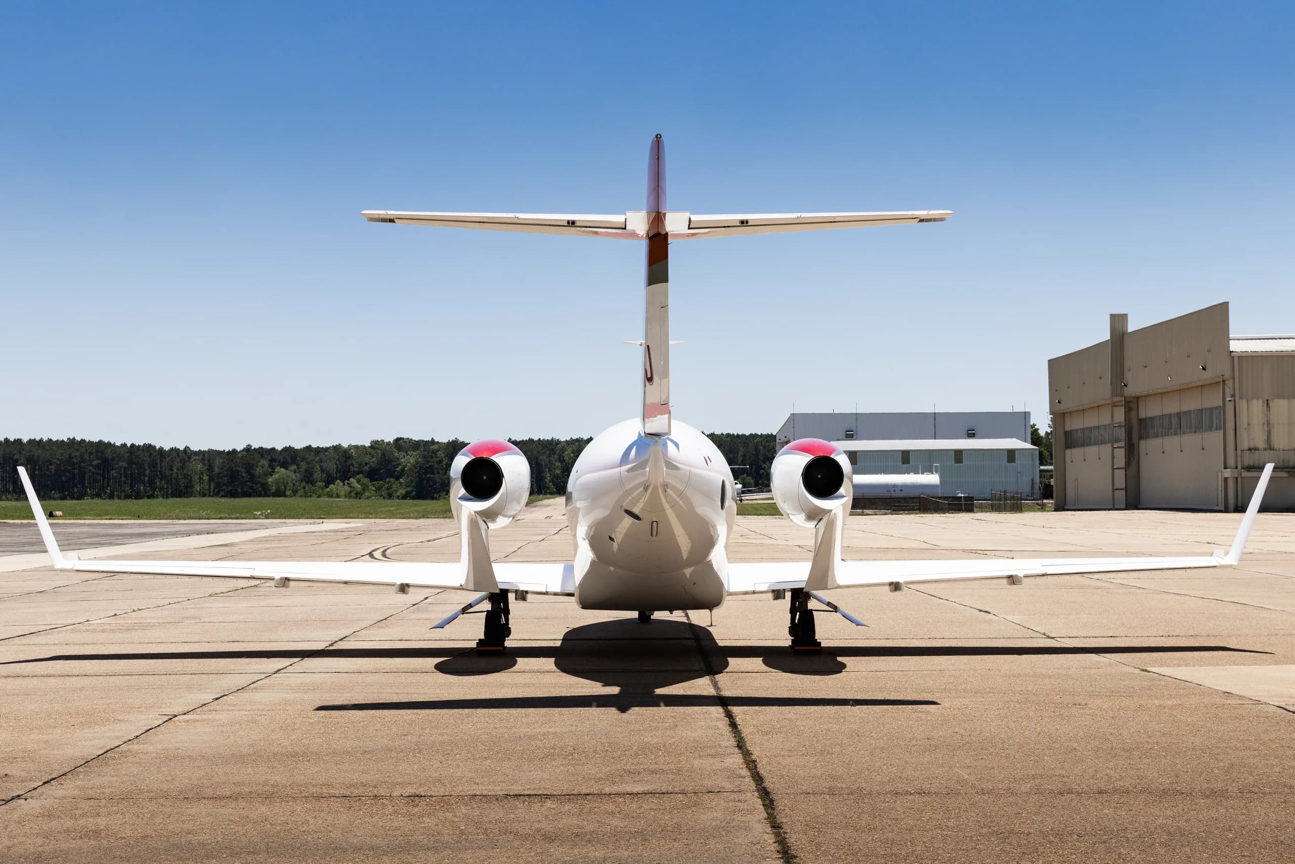 A white and red HondaJet HA-420 (N30HJ) parked on a tarmac, viewed from the rear.