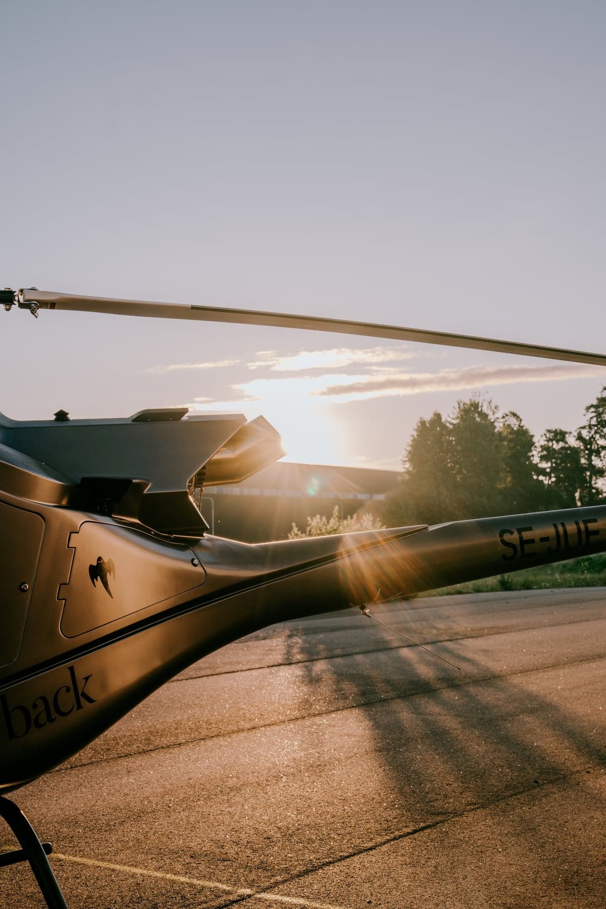 Tail section of a helicopter with the sun setting in the background.